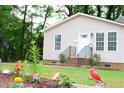 Landscaped front yard with brick stairs, flower garden, and small green bushes leading to beige house at 1536 Granville Street, Burlington, NC 27215