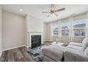 Cozy living room with fireplace, ceiling fan, hardwood floors, and large windows at 256 Summer Ranch Dr, Fuquay Varina, NC 27526