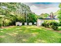 View of backyard with storage sheds and outbuildings surrounded by a well-maintained lawn and mature trees at 2619 Steel Bridge Rd, Sanford, NC 27330