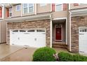 Close-up of a townhome featuring a two-car garage and a welcoming red front door at 270 Wembley Dr, Clayton, NC 27527
