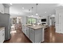 Open-concept kitchen island with a sink, marble countertops, and stainless steel appliances at 3122 Jones Lake Rd, Fuquay Varina, NC 27526