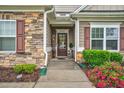 Inviting front entrance with stone accents, a covered porch, and a well-maintained walkway at 3909 Mendenhall Dr, Zebulon, NC 27597