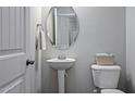 Cozy powder room with a pedestal sink, oval mirror, and neutral wall color at 3909 Mendenhall Dr, Zebulon, NC 27597