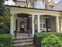 Inviting front porch with stone detailing, white columns, and cozy seating, adding curb appeal to this charming home at 404 Brightling Way, Holly Springs, NC 27540