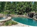 Serene pool area featuring a rock waterfall, lush landscaping, and a tranquil spa for ultimate relaxation and enjoyment at 404 Brightling Way, Holly Springs, NC 27540