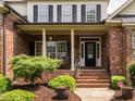 Inviting front porch with brick columns and steps, featuring dark accents and manicured landscaping at 4266 Aviemore Run, Burlington, NC 27215