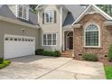 Close-up view of the home's entrance highlighting stone details, a two-car garage, and manicured greenery at 5410 Highcroft Dr, Cary, NC 27519