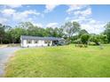Single-story home with a well-manicured lawn, mature trees, and a detached garage at 553 Isley Rd, Haw River, NC 27258