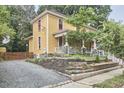 Two-story yellow home showing side yard and driveway, surrounded by mature trees and landscaping at 813 Burch Ave, Durham, NC 27701