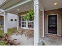 Cozy front porch area with seating for two; fern and dark entry door at 831 Poplar St, Durham, NC 27703