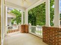 Spacious front porch with brick accents, white railings, and views of the landscaped yard at 102 Westside Dr, Chapel Hill, NC 27516