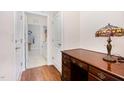 Hallway featuring hardwood floors, a desk with a lamp, and a glimpse into the laundry room at 1528 Anthology Dr, Durham, NC 27703