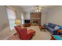 Cozy living room features a brick fireplace, carpeted floors, and natural light from a large window at 20 Banbury Ct, Roxboro, NC 27573