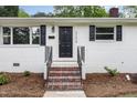 Inviting front entrance featuring a black door, brick stairs, and manicured landscaping at 2205 W Carver St, Durham, NC 27705
