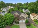 An aerial view showcases this home with mature trees in a residential area and manicured lawn with brick two car garage at 2507 Mayview Rd, Raleigh, NC 27607