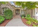 Charming home entrance with a brick and stone exterior and a lush landscaped garden with a stately wooden front door at 2507 Mayview Rd, Raleigh, NC 27607