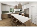 Spacious kitchen with stainless appliances, white cabinets, and a large center island with seating for four at 328 Cottage Hill Way, Raleigh, NC 27604