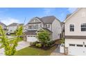 Light gray two-story home with a well-manicured front yard, a two-car garage, and an American flag in view at 348 Golf Vista Trl, Holly Springs, NC 27540