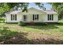 Inviting single-story home featuring a classic white facade, dark shutters, and a cozy front porch at 3627 Nc 57, Hillsborough, NC 27278
