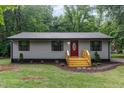Charming single-story home with a gray exterior, a red front door, and a freshly stained natural wood porch and steps at 4420 W River Rd, Franklinton, NC 27525