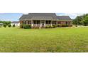 Classic brick home featuring a covered front porch, black shutters and a large front yard at 5136 Liberty Grove Rd, Liberty, NC 27298
