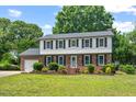 Charming two-story brick home with black shutters, a manicured lawn, and beautiful landscaping at 5409 Knollwood Rd Rd, Raleigh, NC 27609