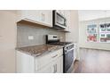 Modern kitchen with granite countertops, stainless steel appliances, and light gray backsplash at 751 Parc Townes Dr # 32, Wendell, NC 27591