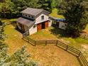 Aerial view of barn with fenced area and sliding wood doors and an attached lean-to for additional shelter at 815 Solitude Pt, Chapel Hill, NC 27516