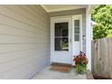 Inviting entryway featuring a glass paneled door, charming welcome mat, and potted flowers at 1816 Piperwood Ct, Durham, NC 27713