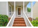 Inviting front porch with brick steps, white railings, and a glass front door with sidelights and overhead light fixtures at 203 Lighthouse Way, Cary, NC 27511