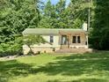 Inviting single-story home with green roof and charming front porch nestled among lush trees at 280 Sagamore Dr, Louisburg, NC 27549