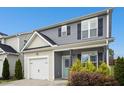 Charming two-story home featuring a white garage door, light green front door and meticulous landscaping at 34 Schoolhouse Way, Clayton, NC 27520