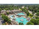 Aerial view of a luxurious community pool with multiple pools, slides, and a clubhouse surrounded by lush greenery at 4003 Jockey Club Cir, Cary, NC 27519