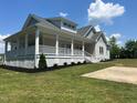 Home featuring a spacious, covered wraparound porch with white columns and railing at 4016 Berman Edge Rd, Holly Springs, NC 27540