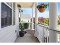 View of the inviting front porch with hanging flower baskets and a cozy, shaded ambiance at 518 Spruce Meadows Ln, Willow Springs, NC 27592