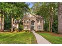 Lovely brick home featuring a manicured lawn, and a curved sidewalk surrounded by mature trees at 7808 Umstead Forest Dr, Raleigh, NC 27612