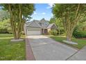 Landscaped front yard with mature trees framing a charming home with a brick and siding exterior at 8517 Evans Mill Pl, Raleigh, NC 27613