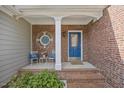 Welcoming front porch with brick columns, a blue door, and cozy seating, offering a relaxing outdoor space at 8517 Evans Mill Pl, Raleigh, NC 27613