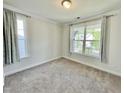 Bright bedroom with plush carpeting, featuring two large windows and neutral wall color, creating a cozy space at 8813 Moss Glen Dr, Raleigh, NC 27617
