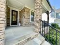 Inviting front porch with stone pillars and elegant black door, offering a charming entrance to the home at 8813 Moss Glen Dr, Raleigh, NC 27617