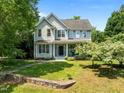 Beautifully landscaped home with a manicured lawn, stone wall, and a variety of trees under a clear blue sky at 100 Michaels Way, Chapel Hill, NC 27516