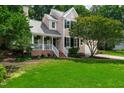 Beautifully landscaped two-story home with a well-manicured lawn, charming porch, and lush greenery at 107 Ivy Hollow Ct, Morrisville, NC 27560