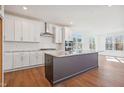 Spacious kitchen with a large island, stainless hood, white cabinetry, and hardwood floors at 11 Little Gem Ln, Fuquay Varina, NC 27526