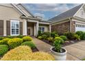 Well-maintained home with lush landscaping, including colorful bushes, stone accents, and two-car garage at 112 Tanoak Ct, Durham, NC 27703