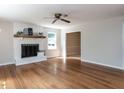 Bright living room with hardwood floors, white brick fireplace, wooden mantle and modern ceiling fan at 113 Honeysuckle Ln, Durham, NC 27703