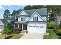 Charming two-story home with light blue siding, stone accents, an attached garage, and a well-manicured lawn at 1132 Heritage Knoll Dr, Wake Forest, NC 27587