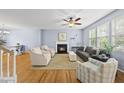 Spacious living room with fireplace, ceiling fan, and hardwood floors, filled with natural light from large windows at 12501 Garden Tree Ln, Raleigh, NC 27614