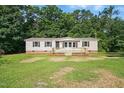 Charming single-story home with tan siding and a wooden porch, nestled among lush green trees at 1392 L Cooper Rd, Cameron, NC 28326