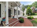Welcoming front door with white pillars, black shutters, brick path, and manicured landscaping at 1404 Kings Lassiter Way, Raleigh, NC 27614