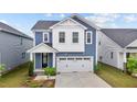 Charming two-story home featuring blue siding, white trim, a two-car garage, and manicured landscaping at 159 Wood Orchid Ln, Garner, NC 27529